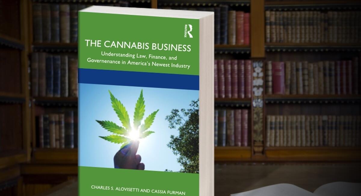 A book in the foreground and a bookshelf in the background with books. the book in the foreground reads “the cannabis business. understanding law, finance, and governance in america’s newest industry.” this book was written by vicente llp attorneys.